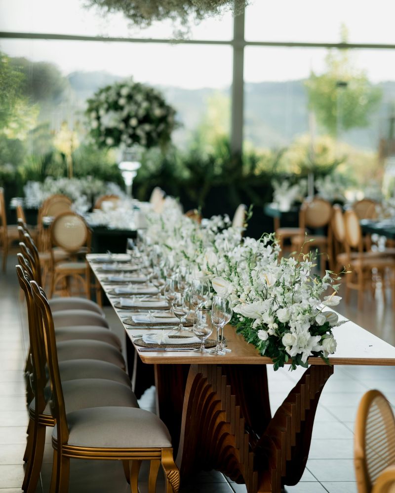 Tavola imperiale con runner di fiori bianchi e verdi in una sala vetrata