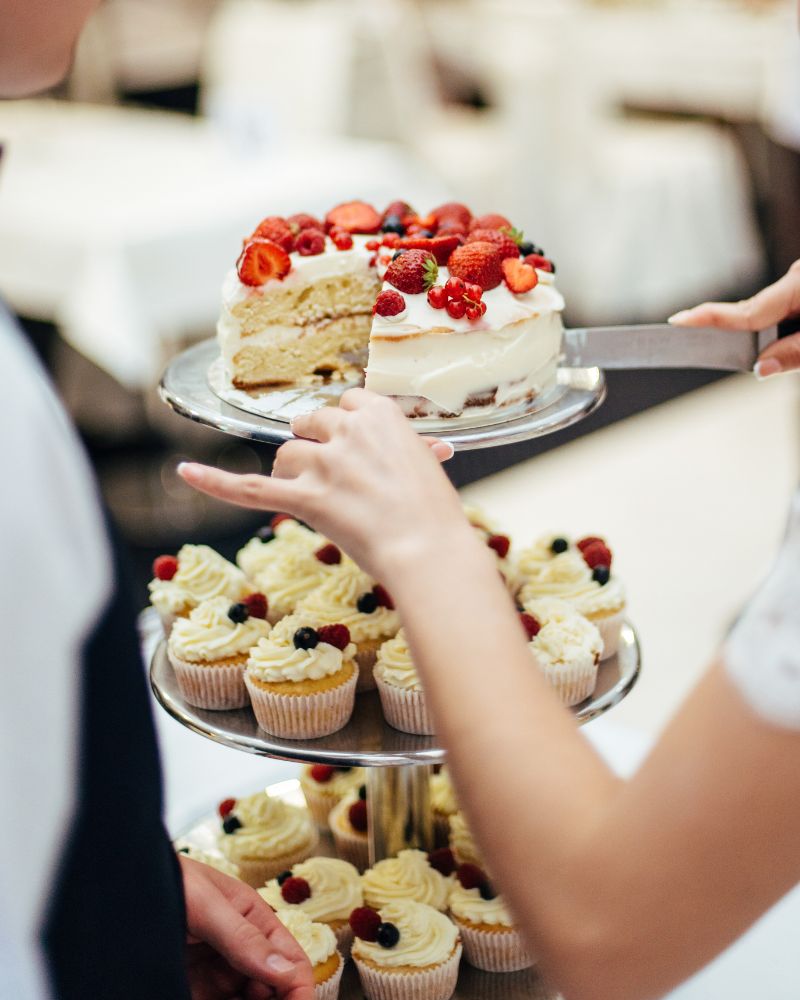 Taglio della torta nuziale a più piani con cupcakes ai frutti di bosco