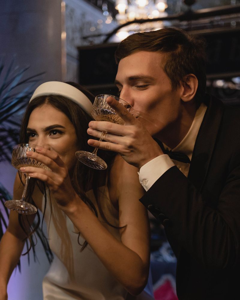 Sposi eleganti che brindano con coupe di cristallo in un interno raffinato